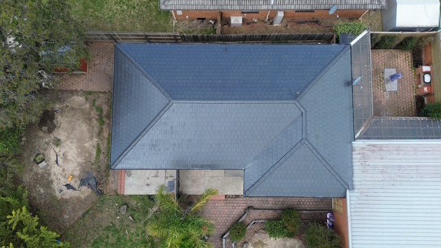 After: roof restoration. Weathered concrete tiles restored in slate grey.