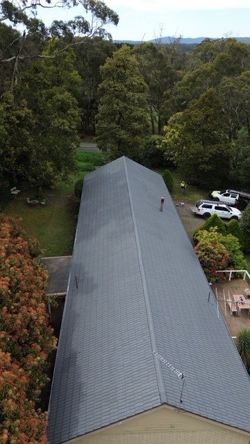After: roof restoration. A long, weathered roof restored and coated grey.