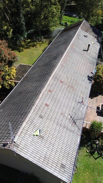 Before: roof restoration. A long, weathered roof restored and coated grey.