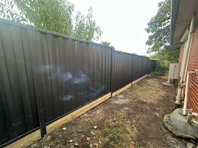 A new steel panel fence along a side path